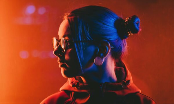 Millennial pretty girl with unusual hairstyle near glowing red neon of city at night. Dyed blue hair in braids. Mysterious hipster teenager in glasses. Reflection of light. Millennial pretty girl with unusual hairstyle near glowing red neon of city at night. Dyed blue hair in braids. Mysterious hipster teenager in glasses. Reflection of light.